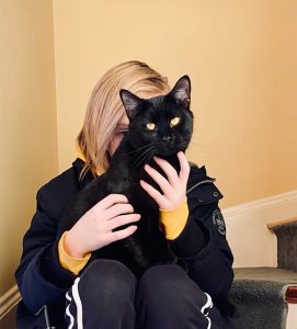 A girl holding up Hayes-a black cat